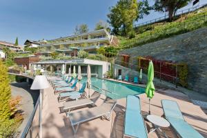 a pool with chairs and umbrellas next to a building at Christophs Hotel in Schenna