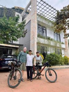a group of three men standing next to their bikes at Cúc Phương Mebi Hotel in Phủ Nho Quan