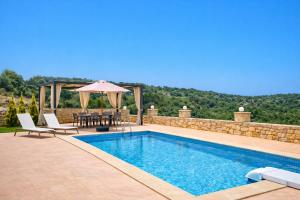 a swimming pool with a table and an umbrella at Natural view villa with private pool in Skouloúfia