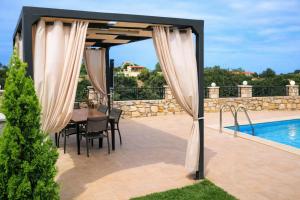 a gazebo with a table and chairs and a pool at Natural view villa with private pool in Skouloúfia