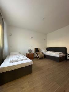 ein Zimmer mit zwei Betten und einem Stuhl in der Unterkunft Willkommen24 in Pfullingen