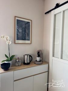 a shelf with a coffee maker and flowers on it at Plumards, maison d'invités proche Abbaye in Argoules