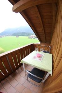 a table and chairs on a balcony with a view of a field at Christina's Bergblick in Oberammergau