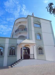 a large white building with a balcony on top at Ras Al Hadd Guest House in Al Ḩadd