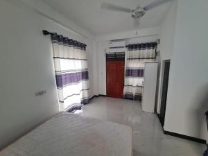 a room with a bed and two windows and a door at A & S residences in Pannipitiya