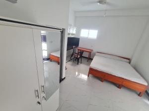 a room with two beds and a table and a door at A & S residences in Pannipitiya