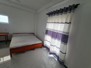 a small room with a bed and a curtain at A & S residences in Pannipitiya