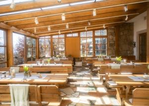 a large dining room with wooden tables and windows at Neubichler Alm in Piding