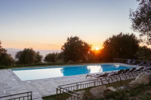 a pool with chairs and the sunset in the background at Podere Montale Il Borgo in Seggiano