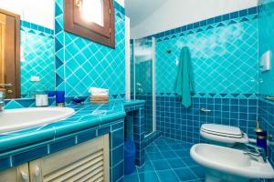 a blue tiled bathroom with a sink and a toilet at Villa Azzurra in Cannigione +22 photos