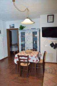 a dining room with a table and chairs and a television at Casa Alpina Place in Isolaccia
