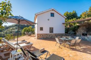 a patio with a table and chairs and an umbrella at Cubo's Casa Mi Recreo High Privacy in Yunquera