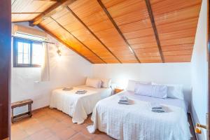 two beds in a room with a wooden ceiling at Cubo's Casa Mi Recreo High Privacy in Yunquera +38 photos