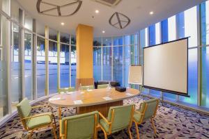 a meeting room with a table and chairs and a screen at Asyana Pemuda Jakarta in Jakarta