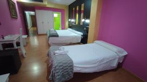 two beds in a room with pink walls at Hotel Aro'S in Casas Ibáñez