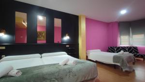two beds in a room with pink and purple walls at Hotel Aro'S in Casas Ibáñez