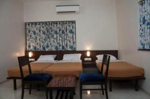 a hotel room with two beds and two chairs at Hotel Regency International in Jamnagar
