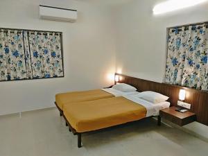 a bedroom with a large bed and two windows at Hotel Regency International in Jamnagar +15 photos