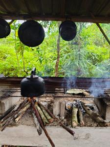 a pot on a tripod next to a fire at Arkana Huis in Perawas