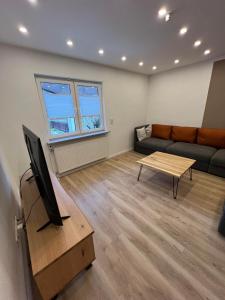 a living room with a couch and a tv at Ferienhaus mit Trifelsblick in Annweiler am Trifels
