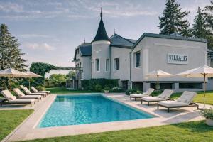 a house with a swimming pool with lounge chairs and umbrellas at Villa17 in Badacsonytomaj