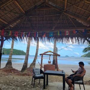 a man sitting at a table on the beach at Island Crib in El Nido