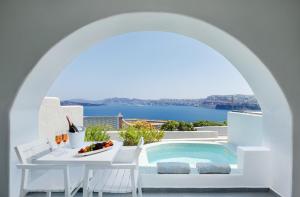a villa with a swimming pool and a table and chairs at Acroterra Rosa Luxury Suites & Spa in Akrotiri