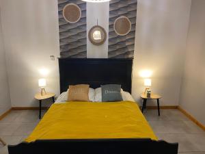 a bedroom with a yellow bed with two side tables at Gîte cosy 6 personnes, avec jardin en Normandie, proche des plages du débarquement et du Mont Saint-Michel in La Luzerne