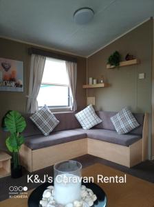 a couch in a living room with a window at K&J's Caravan Rental in Kinmel Bay +30 photos