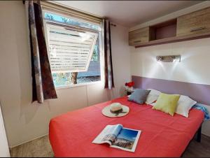 a bedroom with a red bed with a window at Campasun Camping de l'Aigle in Aiguines