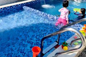 a little girl standing next to a swimming pool at Omah Kebun Private Pool in Sungai Besar