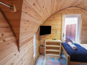 a bedroom in a tiny house with a bed and a tv at Park View Lodge in Derby