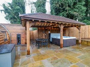 a wooden pavilion with a tub and a table at Park View Lodge in Derby