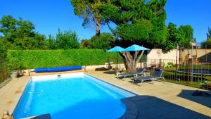 a swimming pool with two chairs and an umbrella at fleur de garance in Le Thor