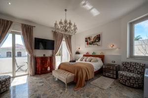 a bedroom with a bed and a chandelier at Pink Moon Private Luxury Villa Secluded Garden 5 Bedroom 4 en suite Bathrooms with Private Pool CAT 6 WiFi Close to Beach in Fontane Bianche +22 photos