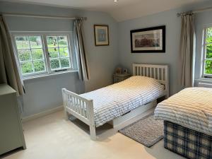 a bedroom with two beds and two windows at Riverside Cottage in Marlborough