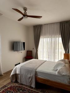 a bedroom with a bed with a ceiling fan and a window at Green Heaven Studio in Bois Chéri