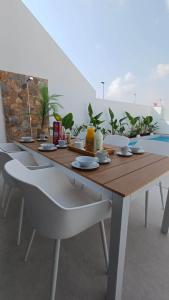 a wooden table with white chairs and a tableasteryasteryasteryasteryasteryasteryastery at Villa Hermana Major Luxury Villa in Las Flamencas in San Javier