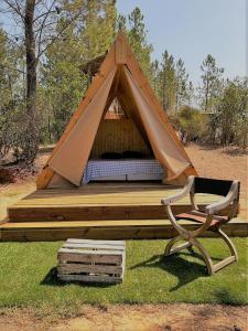 a bed in a tent with a chair in the grass at Parque da Mina in Monchique