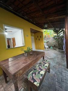 a wooden table in a room with a yellow wall at Casa Canto Verde in Itacaré