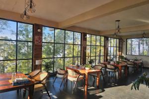 a restaurant with tables and chairs and large windows at ilika Resort - A Boutique Stay 30 km from Devprayag in Pauri