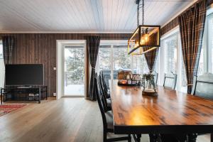 a dining room with a large wooden table and a television at Harmony in Geilo, modern and cozy cabin in Geilo +44 photos