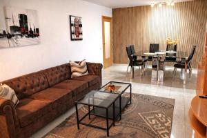 a living room with a brown couch and a dining room at ALEXANDRA´s BEACH-PORT in Badalona