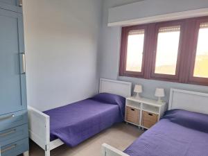 a bedroom with two beds with purple sheets and windows at My Sunset in Torvaianica