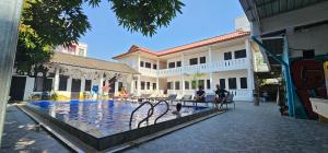 two people sitting next to a swimming pool in a building at Apatuxay Vientiane Hostel in Vientiane