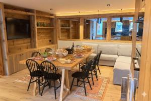 a dining room with a table and chairs and a couch at Les Airelles by Lodji in Saint-Marcel