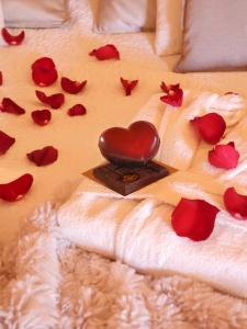 a heart on a bed with red roses on it at Le Cocon des Cinq Sens - l'Insolite in Haute-Goulaine