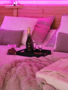 a bottle of wine and two glasses on a bed at Le Cocon des Cinq Sens - l'Insolite in Haute-Goulaine