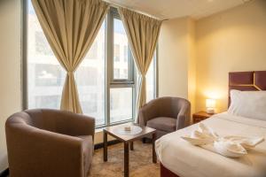 a hotel room with a bed and two chairs and a window at Regal Peninsula Hotel Formerly New Peninsula Hotel Ghubaiba Bus Station Bur Dubai in Dubai