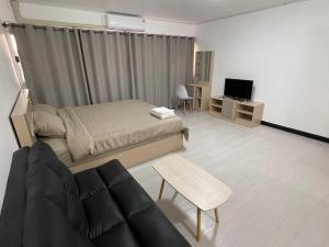 a bedroom with a bed and a couch and a tv at Hi Impact Muangthong T9 in Nonthaburi